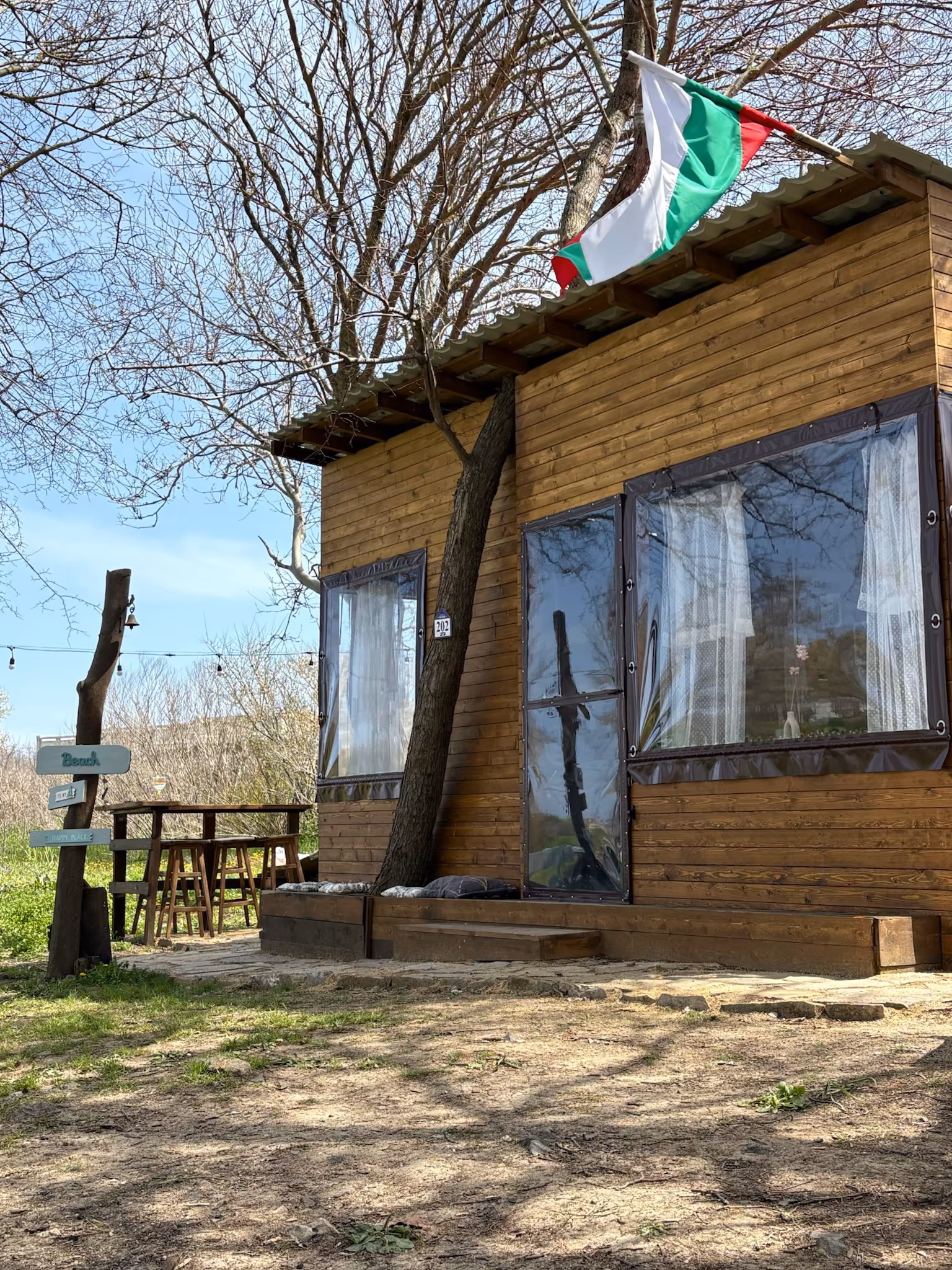 ELYSIUM II отвън — дървена тераса и зеленината около караваната